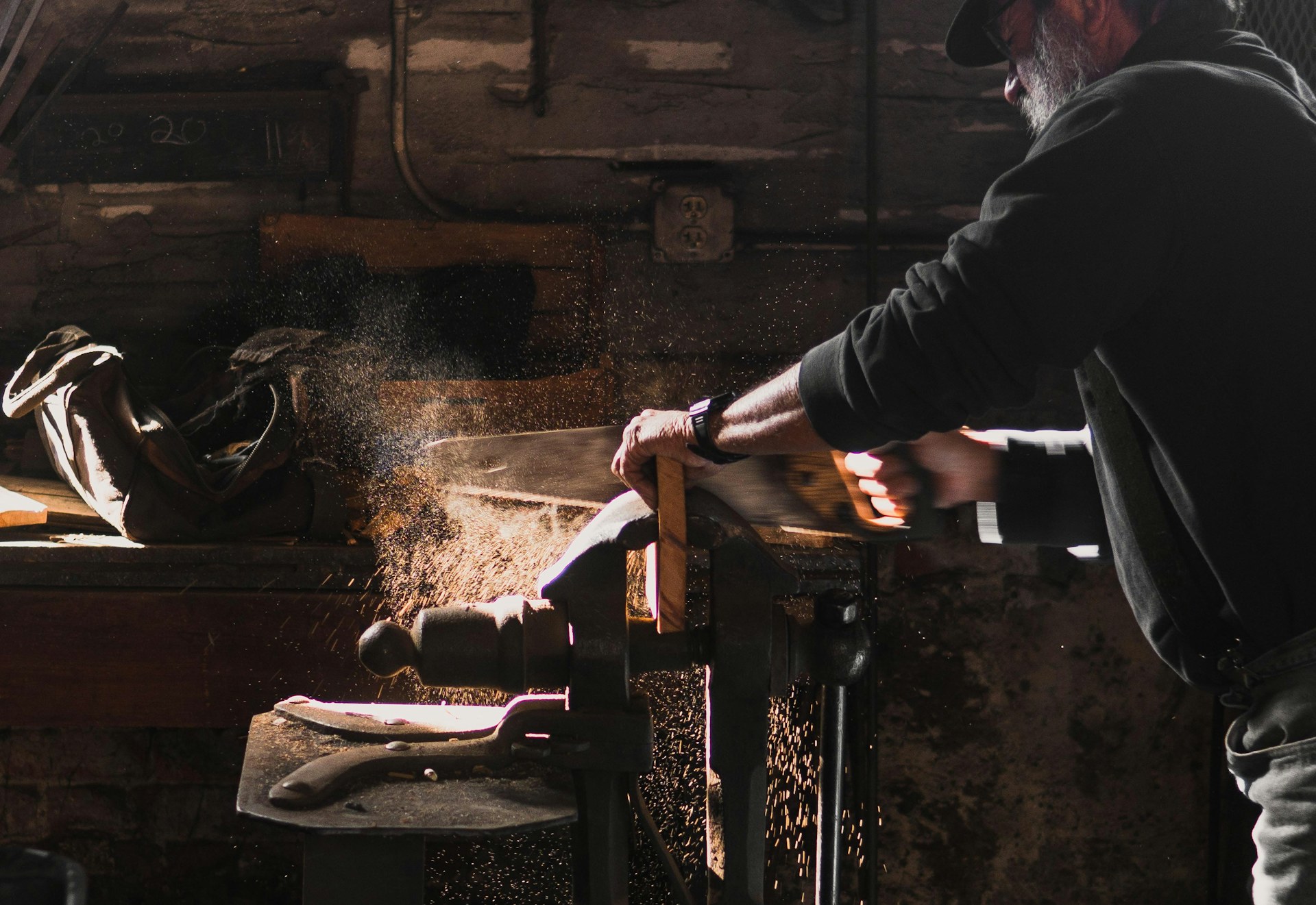 Craftsman hand-sawing timber, dust catching the light — concept imagery
