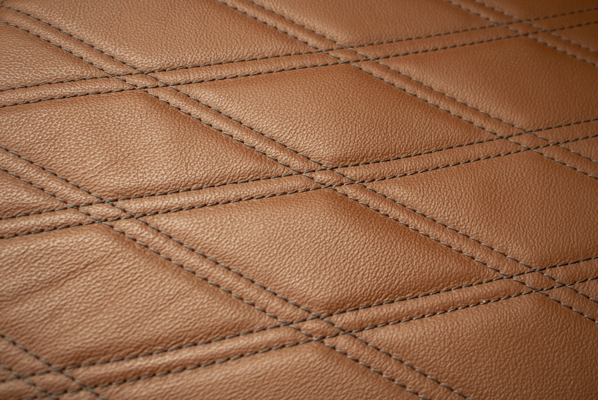 Close-up of quilted caramel leather upholstery stitching